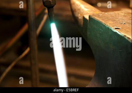 A metal fabricator utilizing a torch to heat up a piece of metal in order to shape it. Stock Photo