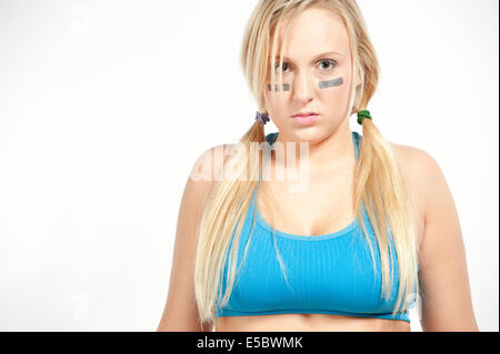 A young blond wearing a sports bra ready to play football on a white background. Stock Photo