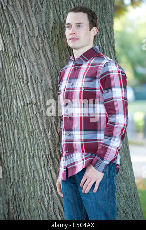 An attractive, fashionable and young male model posing outdoors on a sunny day looking left. Stock Photo