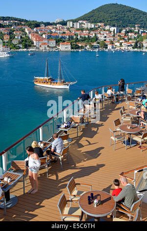 Passengers on cruise ship sunshine deck enjoying outdoor breakfast docked in Dubrovnik Port with part of the town of Gruz beyond Dalmatia Croatia EU Stock Photo