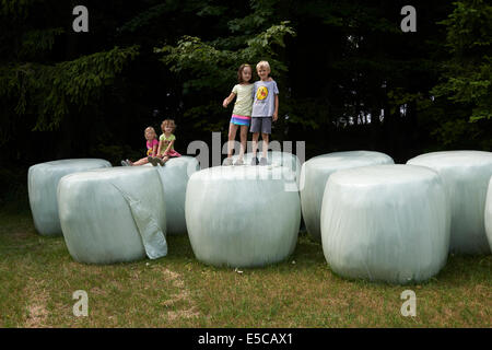 Group of children playing on bales of straw looks like giant teeth, summer time Stock Photo