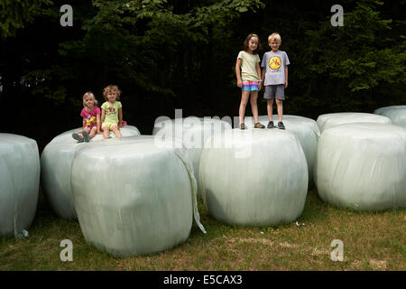 Group of children playing on bales of straw looks like giant teeth, summer time Stock Photo