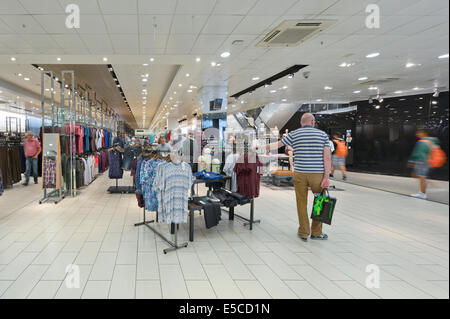 Interior of Next flagship store in the Arndale in Manchester city centre, including a man looking bored. (Editorial use only). Stock Photo