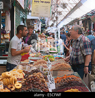 A dried fruit and vegetable vendor with a shopper at Machane Yehuda market, Jerusalem, Israel Stock Photo