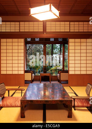 Tea table chabudai and zaisu chairs at traditional Japanese ryokan room with garden view in Gero, Japan Stock Photo