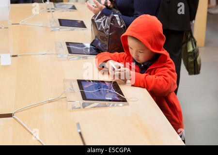 Child using iPhone at Apple store in Ginza, Tokyo, Japan 2014 Stock Photo