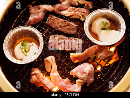 Closeup of beef and scallops being cooked on fire at a Japanese grill restaurant Stock Photo