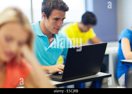 male college student in lecture room using laptop computer Stock Photo