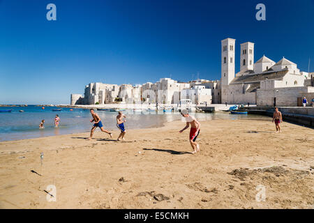 Teenagers playing football onthe beach, harbor, historic centre, Romanesque Old Cathedral, San Corrado and Torrione Passari Stock Photo