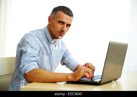 Handsome man using laptop at home Stock Photo