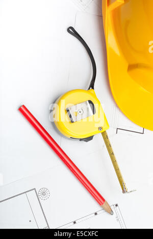 Yellow construction helmet with pencil and measure tape above blueprint Stock Photo
