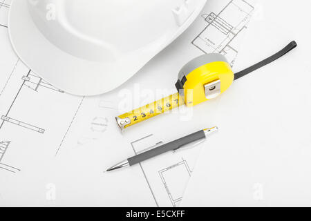 White construction helmet with pencil and measure tape above blueprint Stock Photo