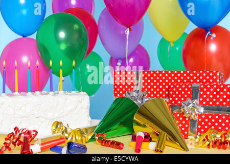 Birthday party still life with cake, balloons, presents, streamers and hats. Stock Photo