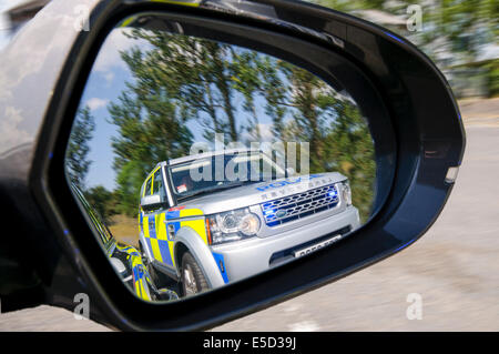 A police Landrover with flashing lights in the door mirror of a car (see also E5AD1H) Stock Photo