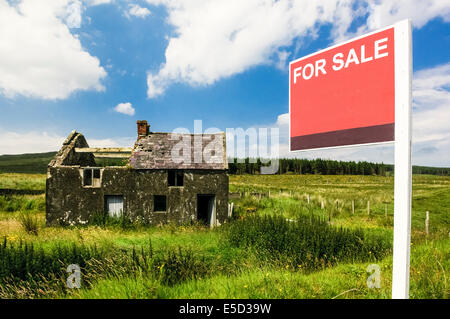Derelict house in a rural hill top situation with blank 'For Sale' sign Stock Photo
