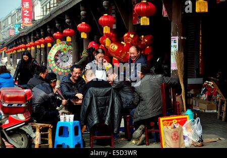 JUN LE TOWN, CHINA:   A group of men playing cards in front of a shop with rows of red fabric lanterns for the Chinese New Year Stock Photo