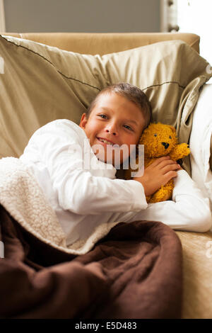Boy resting on bed with teddy