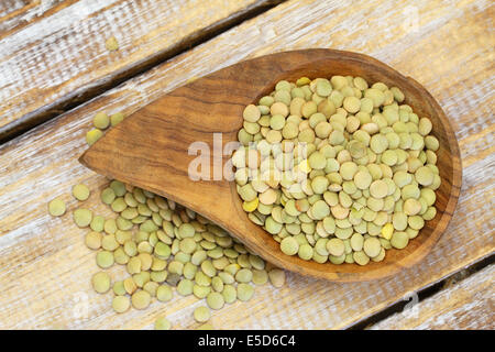 Green lentils in wooden bowl on wooden surface Stock Photo