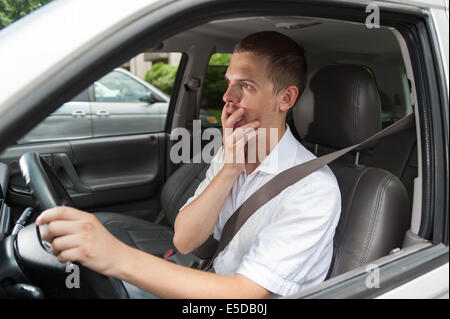 Young caucasian driver is shocked and holding his hand on his mouth Stock Photo