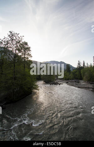 The Sun setting behind the mountains, over the Elwha River in the Pacific Northwest Stock Photo