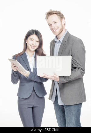 Multi race entrepreneurs. Caucasian man and asian girl happy using technology gadgets. Stock Photo
