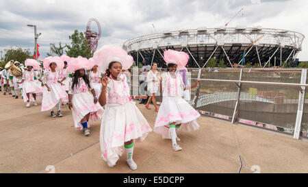 Queen Elizabeth Olympic Park, Stratford, London, UK, 27 July 2014.  The Great British Carnival celebrates the second anniversary of the Opening Ceremony of the London 2012 Olympic Games as well as marking the midway point between the London and Rio Olympics.  There were pop-up parades with music, costumes and samba.  Pictured : dancers pass by the Olympic Stadium.  Credit:  Stephen Chung/Alamy Live News Stock Photo