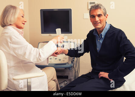 Male patient undergoing wrist ultrasound with female doctor. Stock Photo