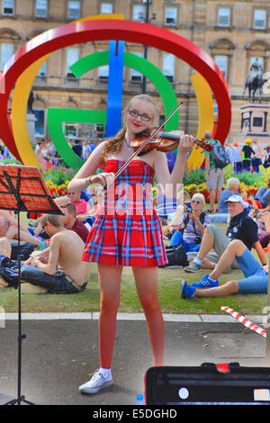 Glasgow, Scotland, UK. 28th July, 2014. Young girl wearing a tartan dress entertains the crowds in glorious sunshine with her violin playing in George Square, Glasgow. Credit:  PictureScotland/Alamy Live News Stock Photo