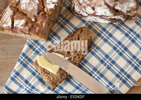 Buttering slice of wholemeal bread, elevated view Stock Photo