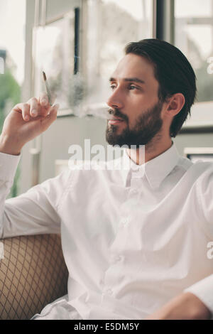 Portrait of young man smoking cigarillo Stock Photo