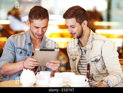 Two young men / students using tablet computer in cafe Stock Photo