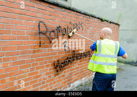 Belfast, Northern Ireland. 29th July, 2014. A council worker removes graffiti saying 'Romanians R [sic] Housebreakers' spraypainted  on a wall in Belfast. Credit:  Stephen Barnes/Alamy Live News Stock Photo