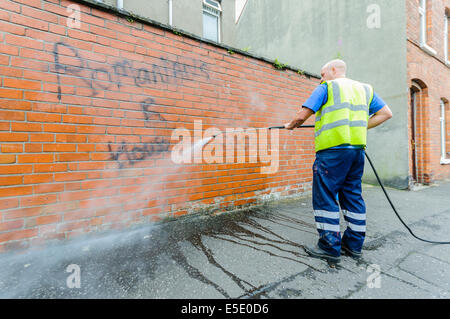 Belfast, Northern Ireland. 29th July, 2014. A council worker removes graffiti saying 'Romanians R [sic] Housebreakers' spraypainted  on a wall in Belfast. Credit:  Stephen Barnes/Alamy Live News Stock Photo