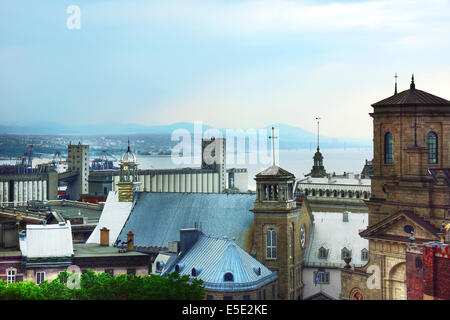 Old Quebec city skyline with tin rooftops and churches, St.Lawrence river and bridge in the background. Stock Photo