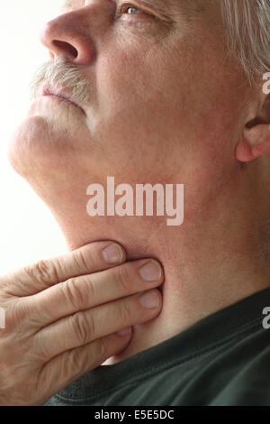 Senior man touches the area of his throat pain. Stock Photo