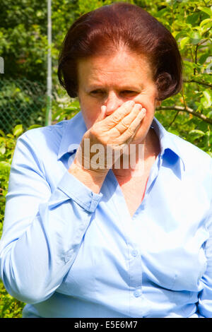Portrait of senior woman sneezing Stock Photo