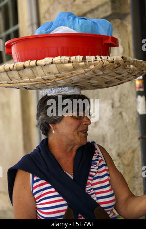 Portuguese woman carrying laundry basket on her head Stock Photo