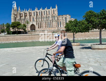 Palma Cycling Mallorca Two cyclists riding near Palma Cathedral in Parc de la Mar Palma historic center Mallorca Spain Stock Photo