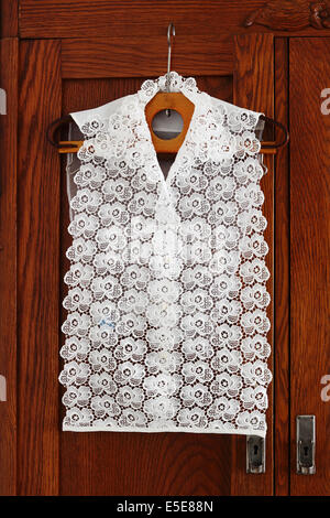 Vintage white lacy dickey hanging on retro hanger on the door of an antique wardrobe Stock Photo