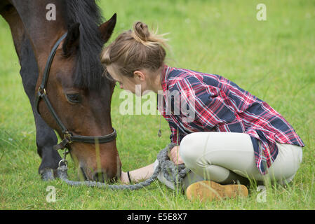 Young teenage girl sitting in a field with her pony. Stock Photo