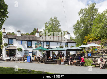 The Britannia Inn, a whitewashed free house country pub in the village of Elterwater, Lake District, Cumbria with umbrellas for outside dining Stock Photo
