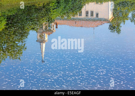 A reflection of a spired church on rippling water with foam flecks in Frankfort, Maine. Stock Photo