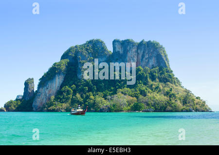 Thai Long Tail boat in front of a craggy island near Krabi, Thailand Stock Photo