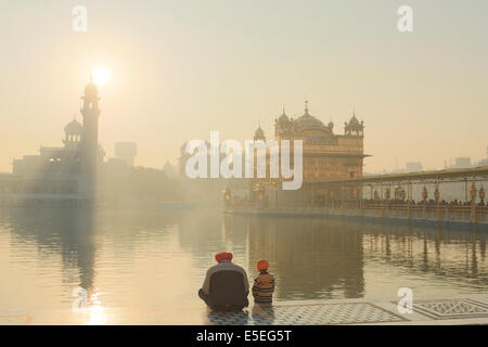 A father and son praying at the Sikh Golden Temple in Amritsar, Punjab, India Stock Photo