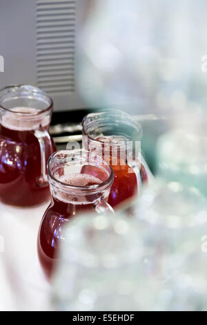 upside-down glasses on counter with gugs of red drink Stock Photo