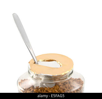 Metal teaspoon rests in a freshly opened jar of aromatic instant coffee granules - with copy space, isolated on white Stock Photo