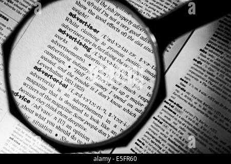 Magnifying glass on the advertising in dictionary. Selective focus on word advertising. Stock Photo