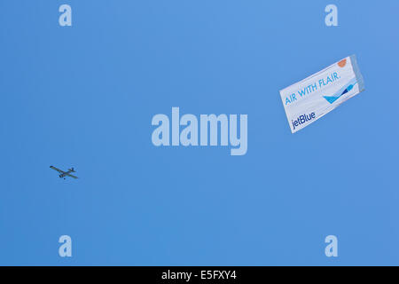 Banner Towing Aircraft Tows Aerial Advert Over Long Beach Waterfront On A Summer Weekend. Stock Photo
