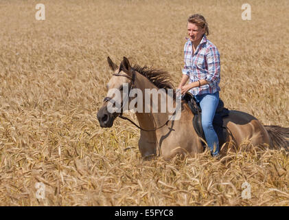 Young woman on horseback in the rye field