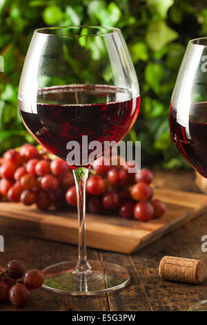 Refreshing Red Wine In a Glass with Grapes Stock Photo